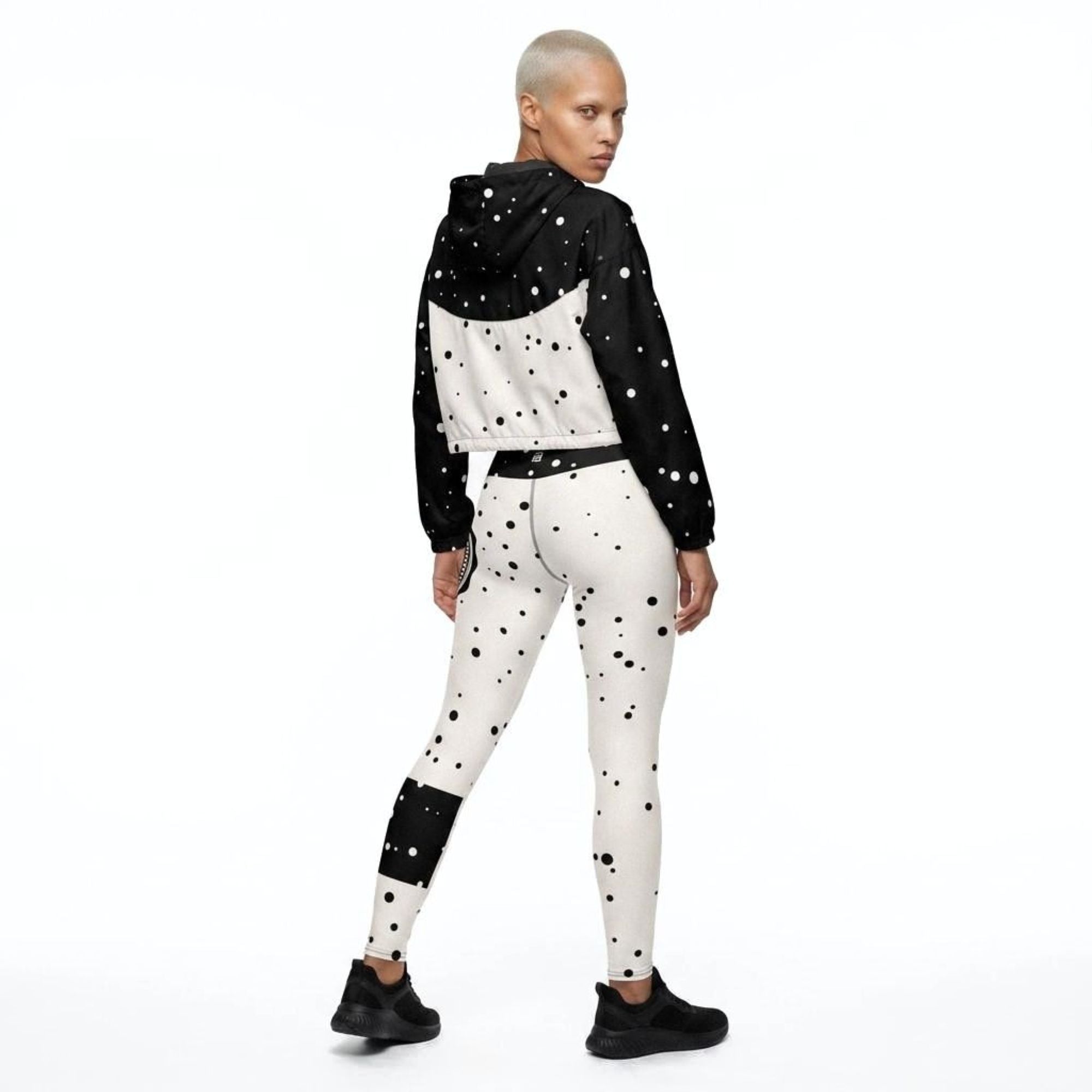 Model wearing God Approved matching activewear set consisting of a cropped windbreaker and leggings, with polka dot pattern, back view