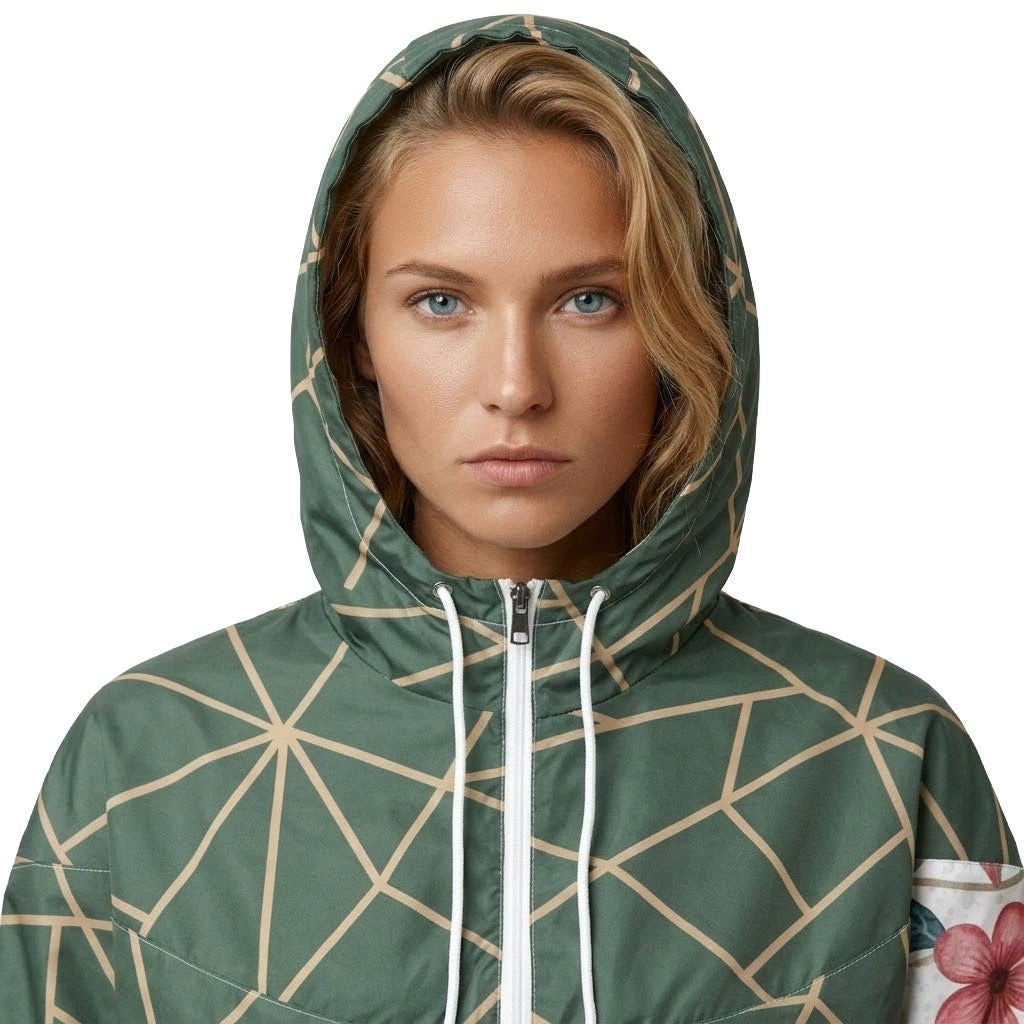 Model wearing Work of Art Cropped Windbreaker in Green with hood on. Has floral design and geometric accents in green.